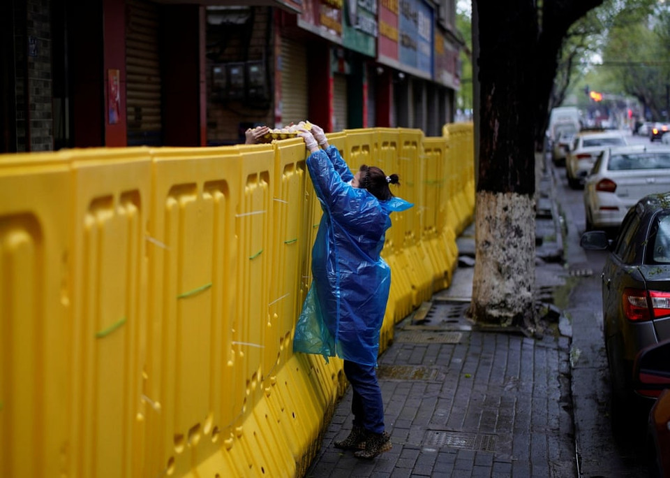 Người dân chuyển thực phẩm qua rào chắn khu cách ly. (Ảnh: Reuters)