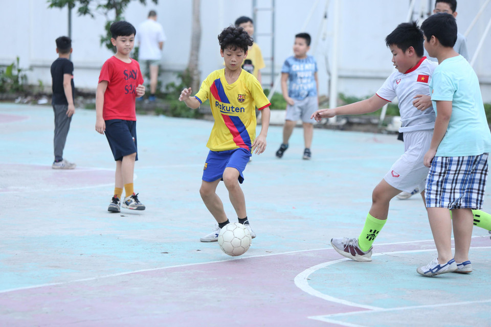 Nhiều em nhỏ tập trung chơi bóng đá mà không đeo khẩu trang và có tiếp xúc gần. (Ảnh: Nguyên An/Vietnam+) /