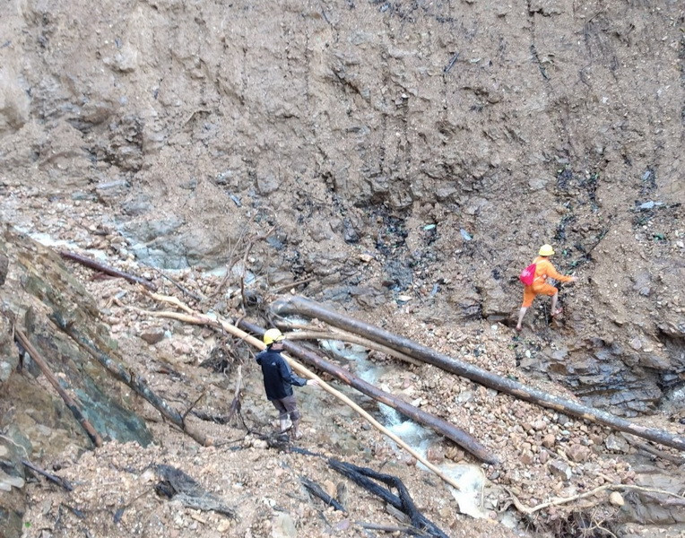 Cho đến thời điểm này, ở 2 thôn này đường chưa nối lại nên các công nhân Điện lực Khe Sanh vẫn phải leo bộ vào. (Ảnh: Thủy Trần/Vietnam+)