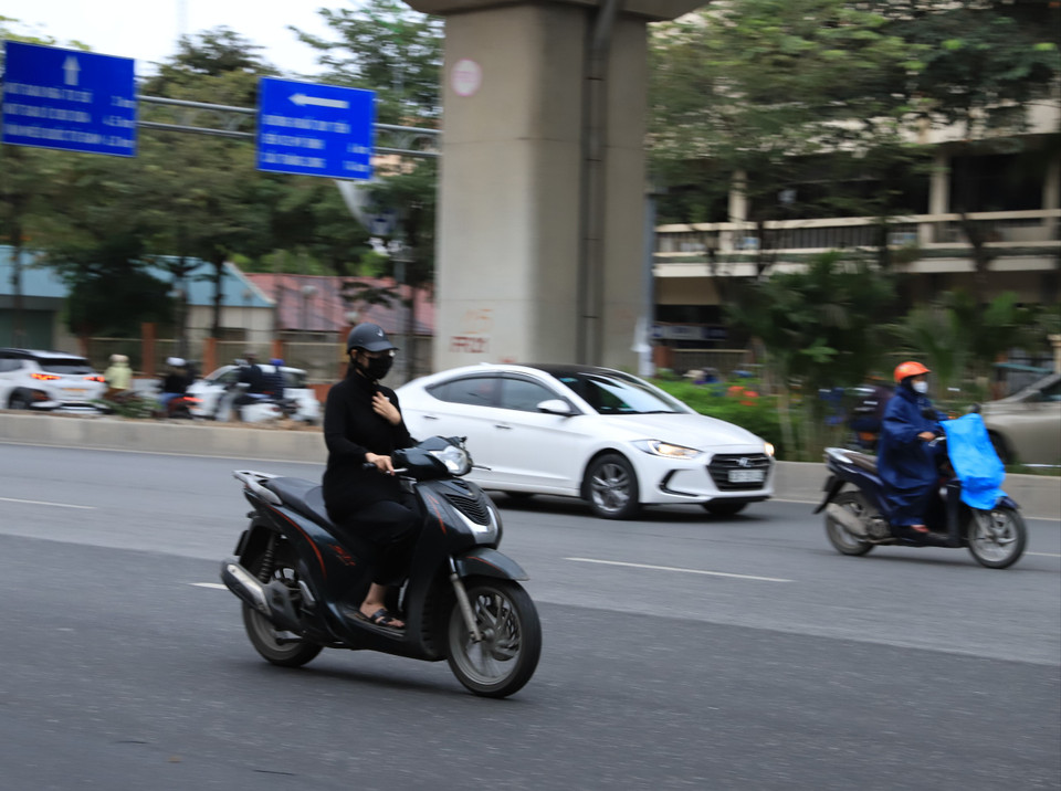 Thời tiết lạnh khiến nhiều người phải một tay điều khiển xe, một tay giữ áo để ngăn cái lạnh đầu mùa. (Ảnh: Hoài Nam/Vietnam+)
