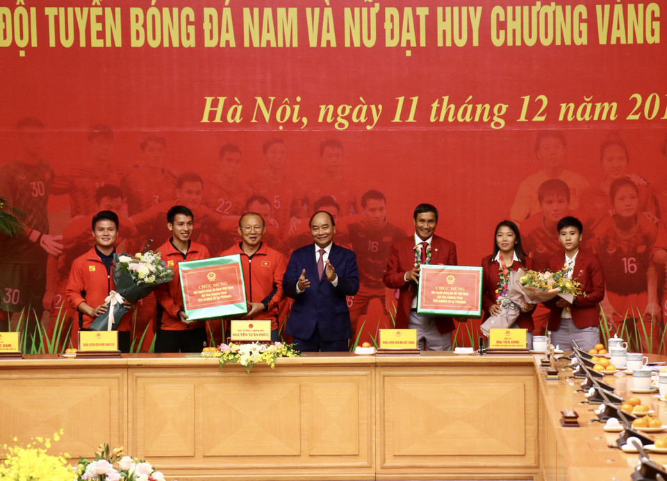 Đại diện hai đội tuyển vui mừng nhận phần quà tại buổi lễ gặp mặt tại Văn phòng Chính phủ cùng Thủ tướng. (Ảnh: Nguyên An/Vietnam+)