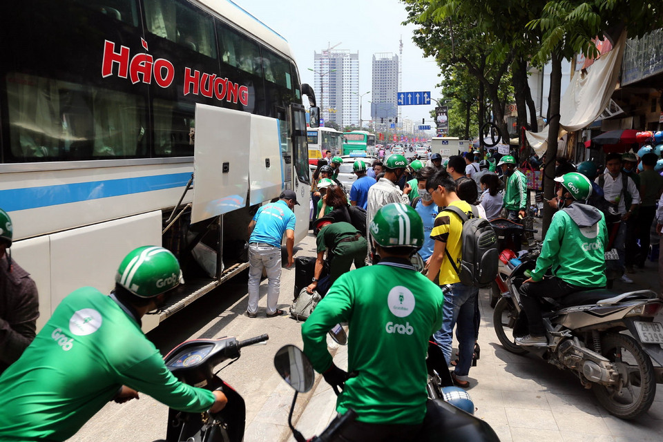 Dịch vụ xe Grab đón khách ngay khi hành khách xuống xe trên đường Giải Phóng. (Nguồn: Danh Lam/TTXVN)