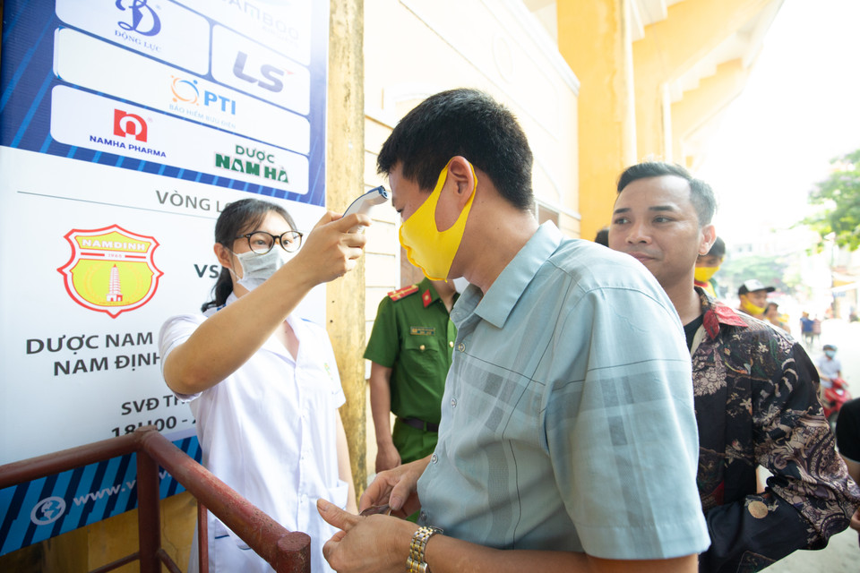 Trước khi vào sân theo dõi trận đấu, cổ động viên phải đeo khẩu trang, rửa tay bằng dung dịch sát khuẩn và được đo thân nhiệt. (Ảnh: Nguyên An/Vietnam+)