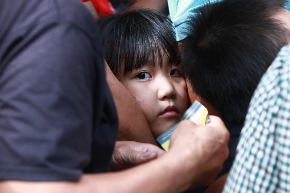 Một em nhỏ bị kẹt cứng giữa dòng người xếp hàng chờ soát vé để vào sân Thiên Trường theo dõi trận Nam Định với Hoàng Anh Gia Lai. Đây là hình ảnh dễ bắt gặp khi các em được người thân đưa đi theo dõi những trận cầu đinh tại sân vận động. (Ảnh: Nguyên An)