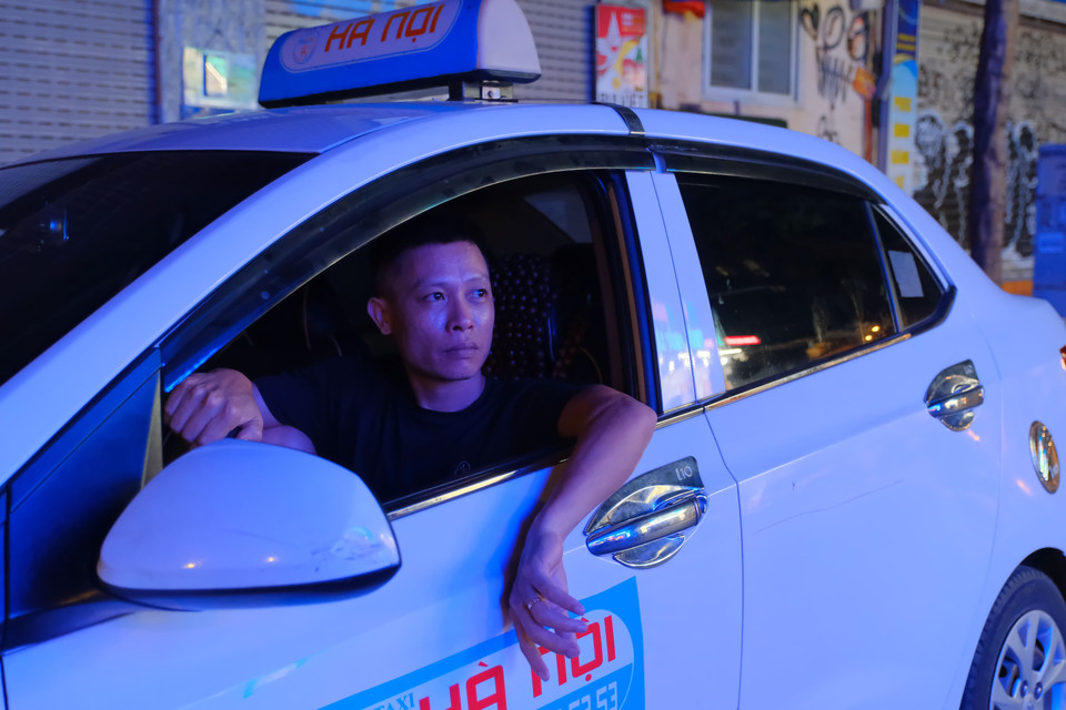Tài xế taxi tranh thủ xem trận đấu sau khi vừa trả khách (Ảnh: PV/Vietnam+)