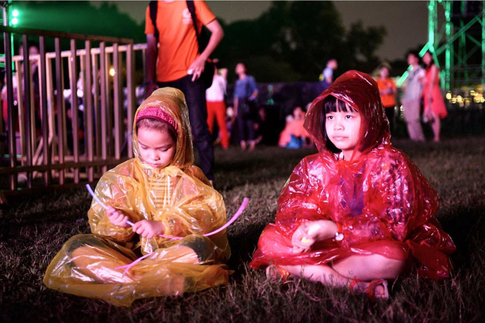 Các em không quản 'đội mưa' ngồi trên bãi cỏ nghe nhạc. (Ảnh: BTC)