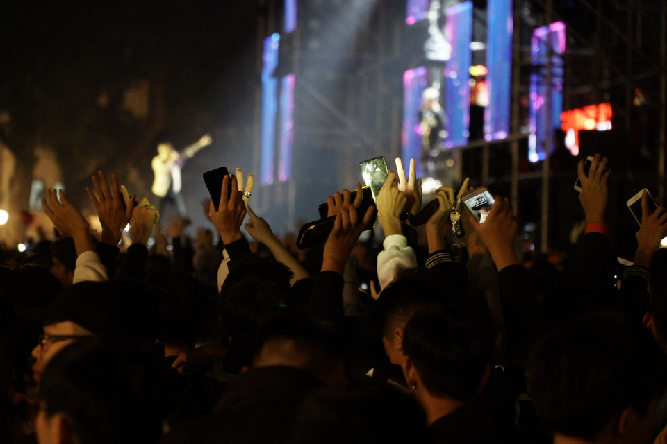 Người dân chiếu đèn điện thoại hòa cùng điệu nhạc trên sân khấu. (Ảnh: Minh Hiếu/Vietnam+)