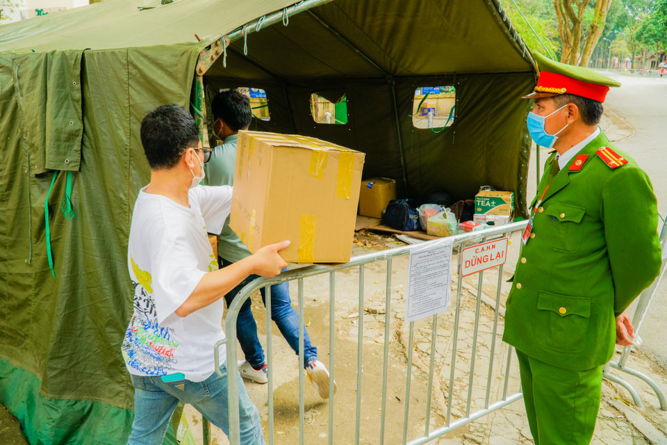 Người dân lỉnh kỉnh mang nhu yếu phẩm đến giao cho lực lượng bồ đội nhờ mang vào điểm tập trung đồ tiếp tế. (Ảnh: Minh Hiếu/Vietnam+)