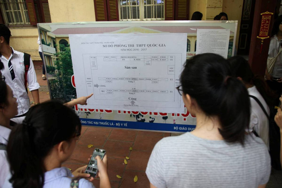 Các thí sinh xem sơ đồ phòng thi trước khi vào làm thủ tục dự thi tại trường Trung học Phổ thông Trần Phú. (Ảnh: Doãn Đức/Vietnam+)