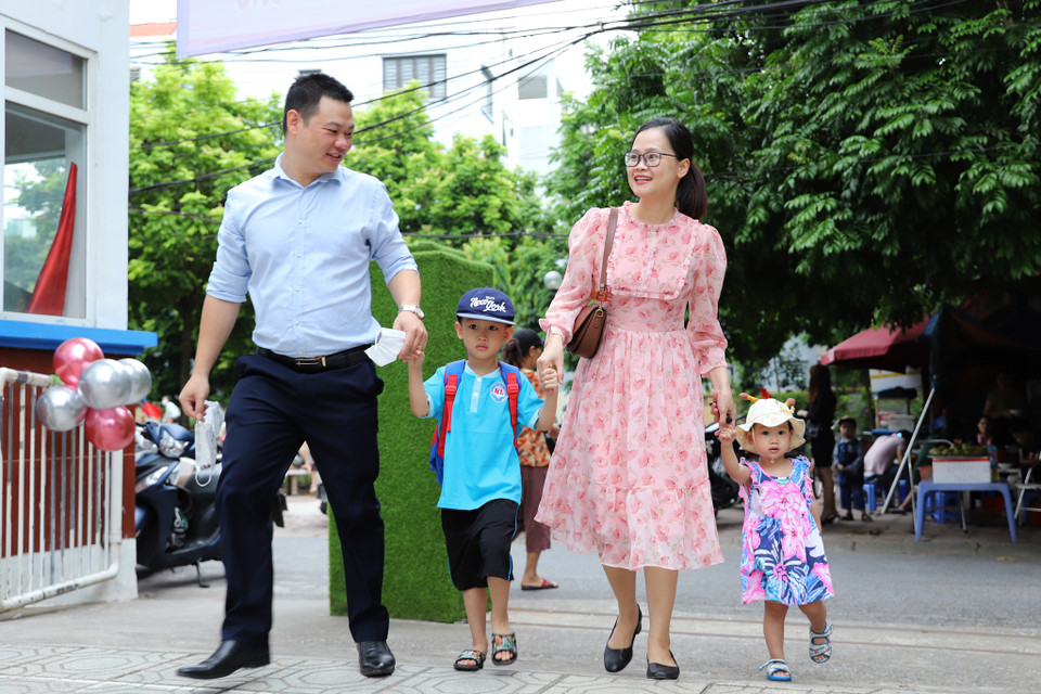 Gia đình anh Nguyễn Công Lưu (Hoàng Mai, Hà Nội) đưa hai con đến trường mầm non trong niềm vui hân hoan. Anh chia sẻ: ‘Các cháu háo hức 3 hôm nay rồi, hôm nào cũng nhắc thứ Hai con đi khai giảng.’ (Ảnh: Hoài Nam/Vietnam+)
