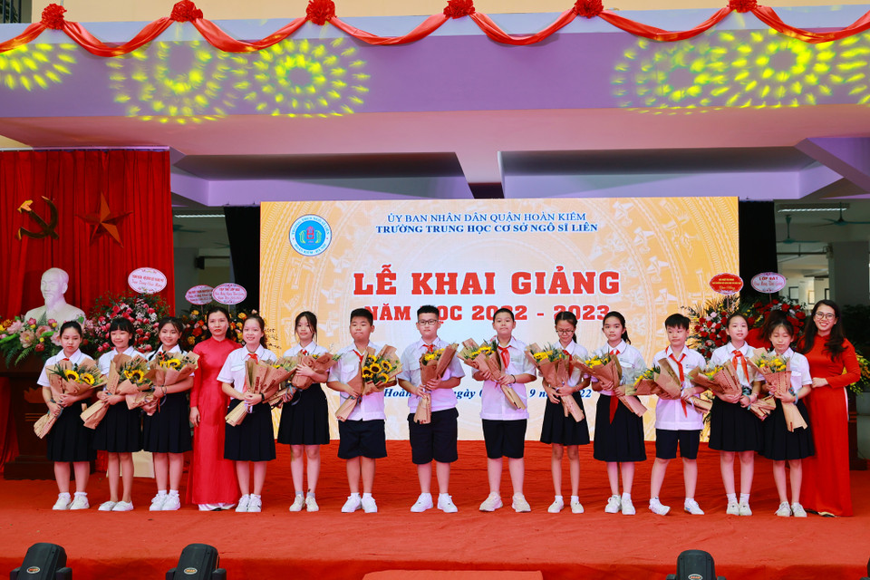 Các em học sinh đại diện học sinh khối lớp 6 nhận hoa từ nhà trường, bắt đầu năm học mới đầy hứng khởi và tràn đầy năng lượng. (Ảnh: Hoài Nam/Vietnam+)