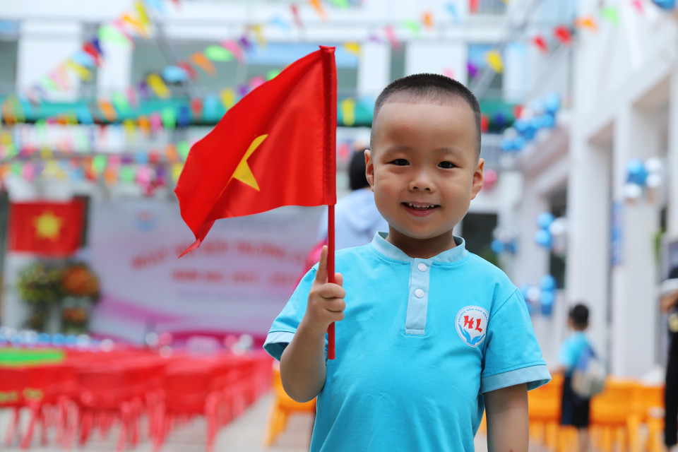 Bạn nhỏ hào hứng cầm trên tay lá cờ Tổ quốc tham dự lễ khai giảng năm học mới 2022-2023. (Ảnh: Hoài Nam/Vietnam+)