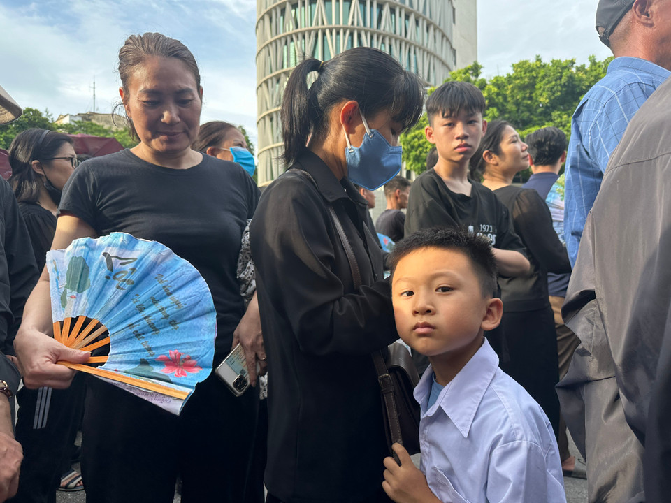 Em bé đi theo mẹ cũng mong được vào viếng Tổng Bí thư. (Ảnh: Vietnam+)