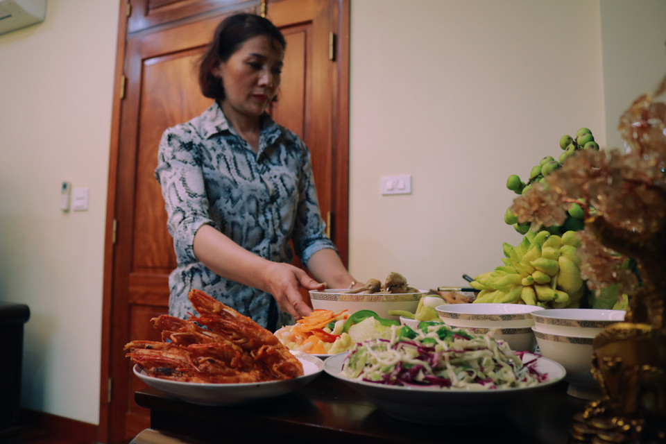 Chị Thuỷ sắp xếp mâm cỗ gọn gàng, chuẩn bị rượu mời ông bà tổ tiên dùng bữa. (Ảnh: Minh Hiếu/Vietnam+)
