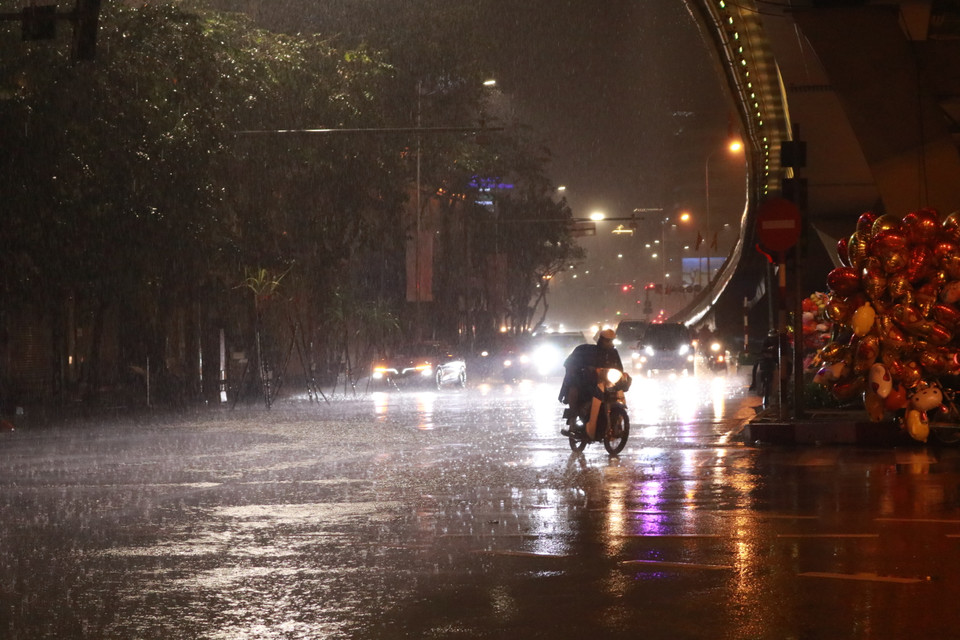 Nhiều người dân khó khăn trong việc tham gia giao thông dưới trời mưa lớn. (Ảnh: Minh Hiếu/Vietnam+)