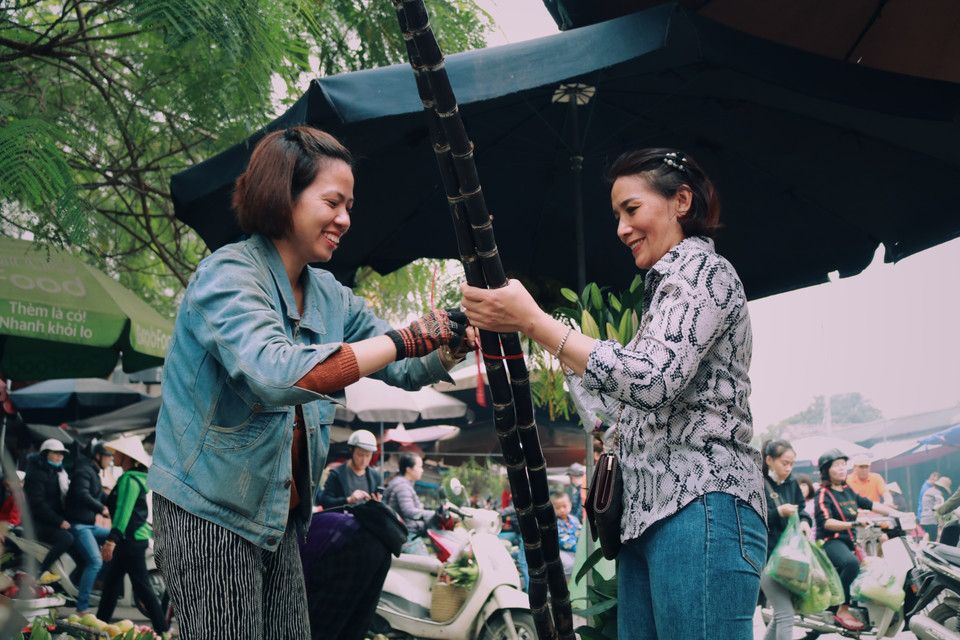 Từ bảy giờ sáng, chị Thuỷ, 47 tuổi, đã dậy sớm ra để chợ chuẩn bị mua thực phẩm và cây mía về cúng Lễ tất niên cho kịp giờ. (Ảnh: Minh Hiếu/Vietnam+)