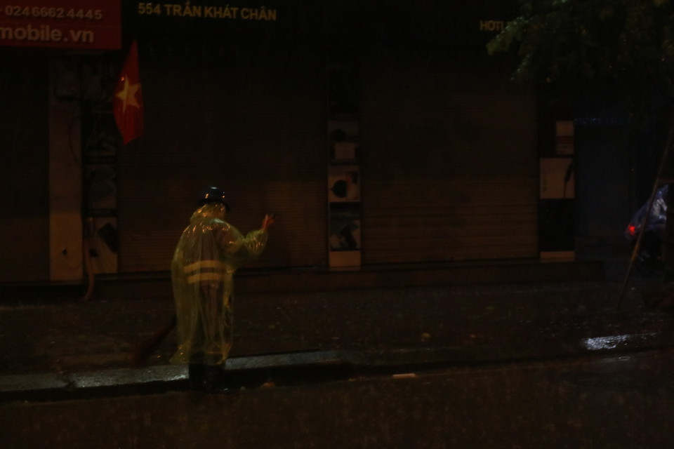 Những người công nhân quét rác vẫn tiếp tục công việc dưới trời mưa tầm tã. (Ảnh: Minh Hiếu/Vietnam+)