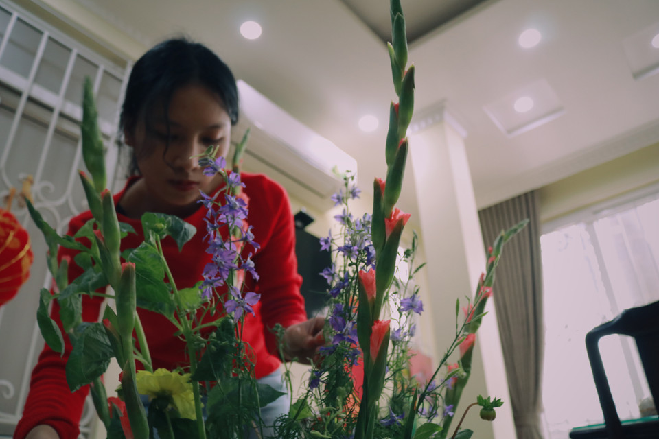 Chị Trang đang cắm những nhành hoa tươi tắn để chuẩn bị mang lên bàn thờ. (Ảnh: Minh Hiếu/Vietnam+)