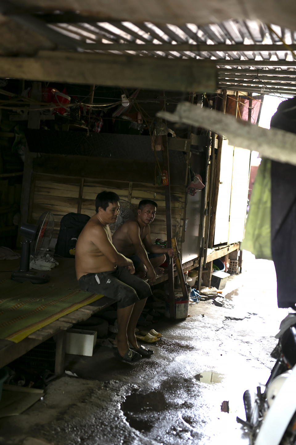 Anh tâm sự: “Ở khu này trưa chiều nóng lắm, tạt nước khắp nơi vẫn nóng, nằm không ngủ được đâu, cứ ngồi nghỉ tạm cho đỡ mệt vậy thôi rồi chiều có việc lại đi làm tiếp.” (Ảnh: Phương Linh/Vietnam+)