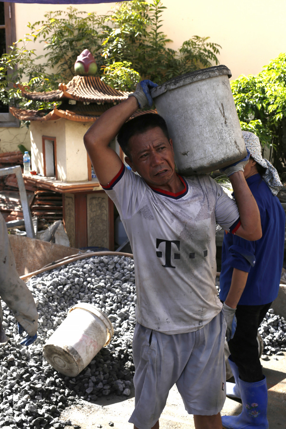 Bao sự vất vả, nặng nhọc gánh trên vai người đàn ông tuổi đã xế chiều, mồ hôi thấm ướt áo càng làm chiếc áo dễ bám bẩn, trở nên nhớp nháp khó chịu. (Ảnh: Phương Linh/Vietnam+)