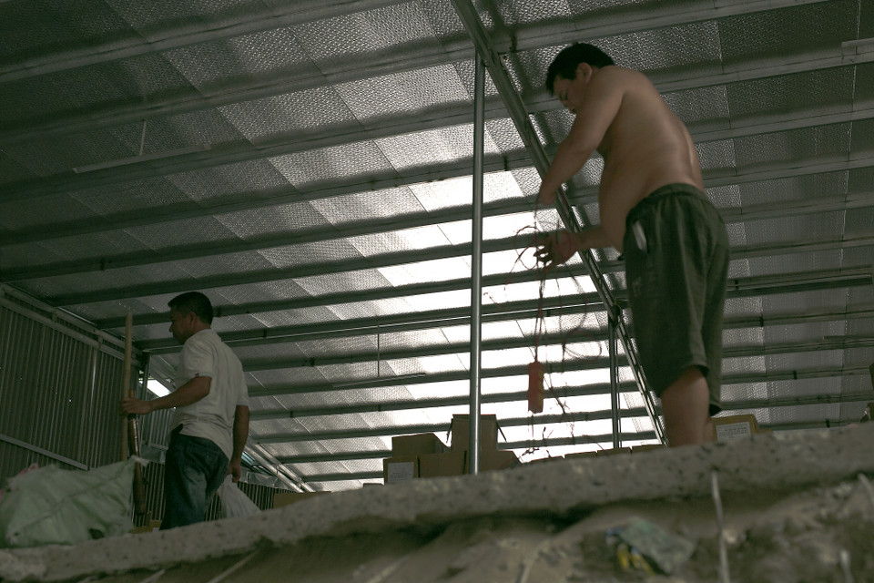 Có những buổi “may mắn” hơn, anh được nhận những công việc đục phá nền trong nhà, trong kho. Tưởng chừng sẽ dễ chịu hơn nhiều ở ngoài, nhưng khi trong kho là 5 mặt tôn đã hấp thụ nhiệt độ nóng bức vào bên trong khiến nơi làm việc như một chiếc “lò bát quái.” (Ảnh: Phương Linh/Vietnam+)