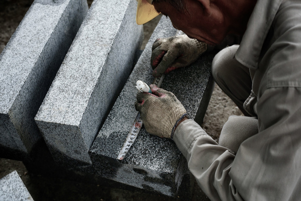 Công nhân phải dùng các thiết bị để đo đạc, đảm bảo độ chính xác khi lắp đặt đá. (Ảnh: Phương Linh/Vietnam+)