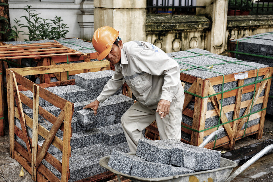 Người công nhân xếp cẩn thận từng viên đá 3kg để chuyển đến vị trí đang làm dở vỉa hè. (Ảnh: Phương Linh/Vietnam+)