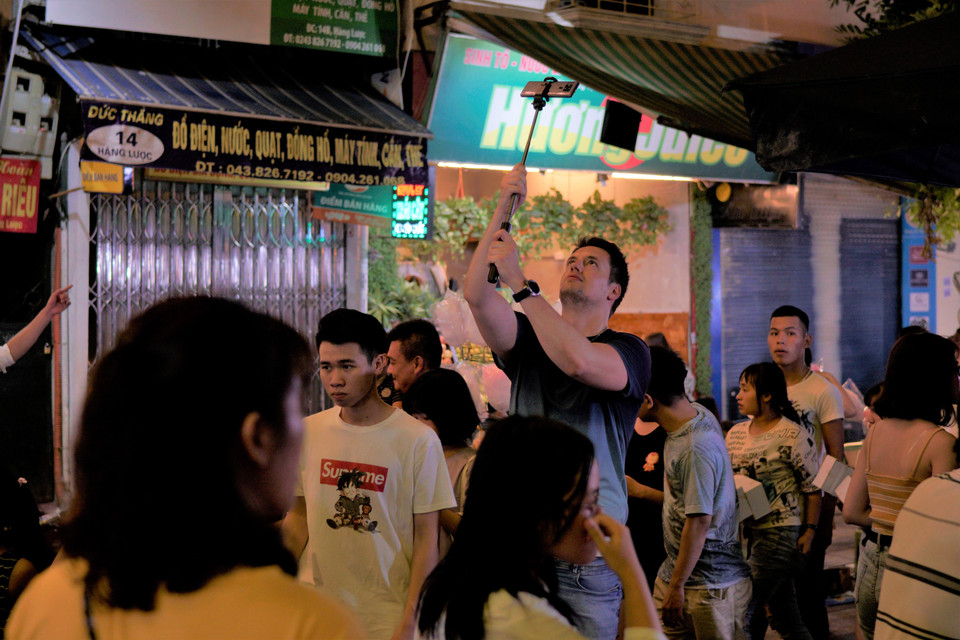 Người nước ngoài đang lưu giữ khoảnh khắc tại con phố. (Ảnh: Minh Hiếu/Vietnam+)