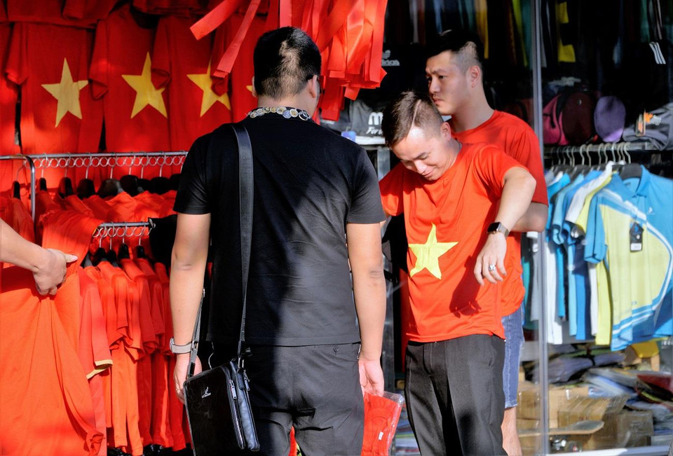 Các cổ động viên mua sắm chiếc áo 'quốc dân' để chuẩn bị tham gia cổ vũ cho đội tuyển. (Ảnh: Minh Hiếu/Vietnam+)