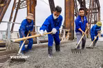Công nhân của đơn vị thi công tiến hành đổ bê tông bề mặt cầu Long Biên. (Ảnh: Hoài Nam/Vietnam+)