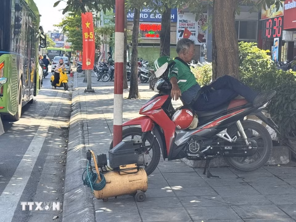 Phút nghỉ ngơi của một tài xế xe ôm công nghệ sau thời gian tham gia giao thông dưới dưới nắng nóng gay gắt lên tới gần 40 độ C. (Ảnh: Quốc Lũy/TTXVN)