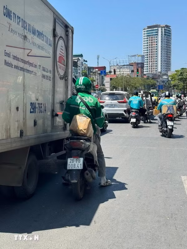 Trên các tuyến đường, người tham gia giao thông vất vả di chuyển dưới hơi nóng hầm hập phả lên từ mặt đường. (Ảnh: Quốc Lũy/TTXVN)
