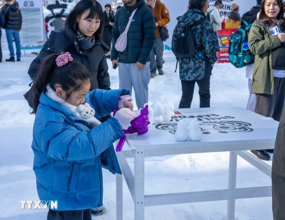 Du khách nhí trổ tài làm tượng tuyết "mini". (Ảnh: Xuân Giao/TTXVN)