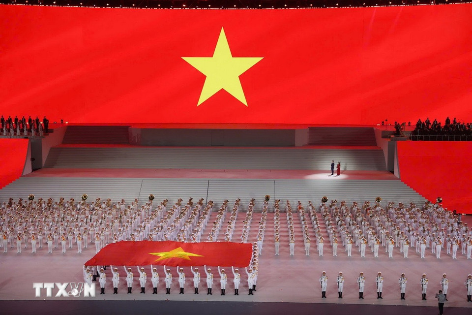 Đại biểu cùng khán giả thực hiện nghi lễ chào cờ. (Ảnh: TTXVN)