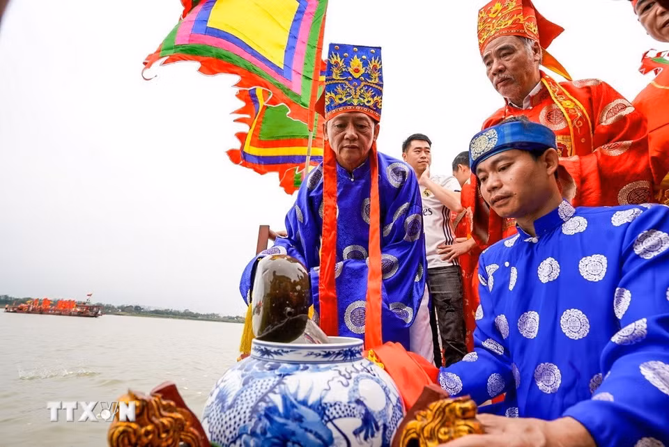 Thực hiện nghi lễ lấy nước từ sông Hồng. (Ảnh: Khánh Hoà/TTXVN)