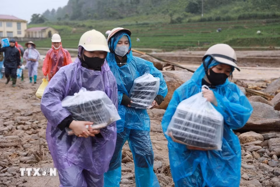 Người dân xã Than Uyên đưa những suất cơm nóng hổi ấm áp tình người cùng nhu yếu phẩm cần thiết đến với nhân dân Bản Chít và các lực lượng giúp dân khắc phục hậu quả do lũ dữ gây ra tại Mường Than. (Ảnh: Quý Trung/TTXVN)