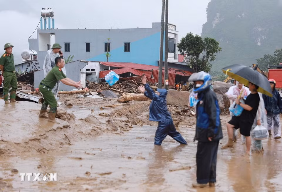Người dân đưa nhu yếu phẩm cho các lực lượng đang hỗ trợ người dân khắc phục hậu quả của lũ dữ gây ra tại xã Mường Than. (Ảnh: Quý Trung/TTXVN)