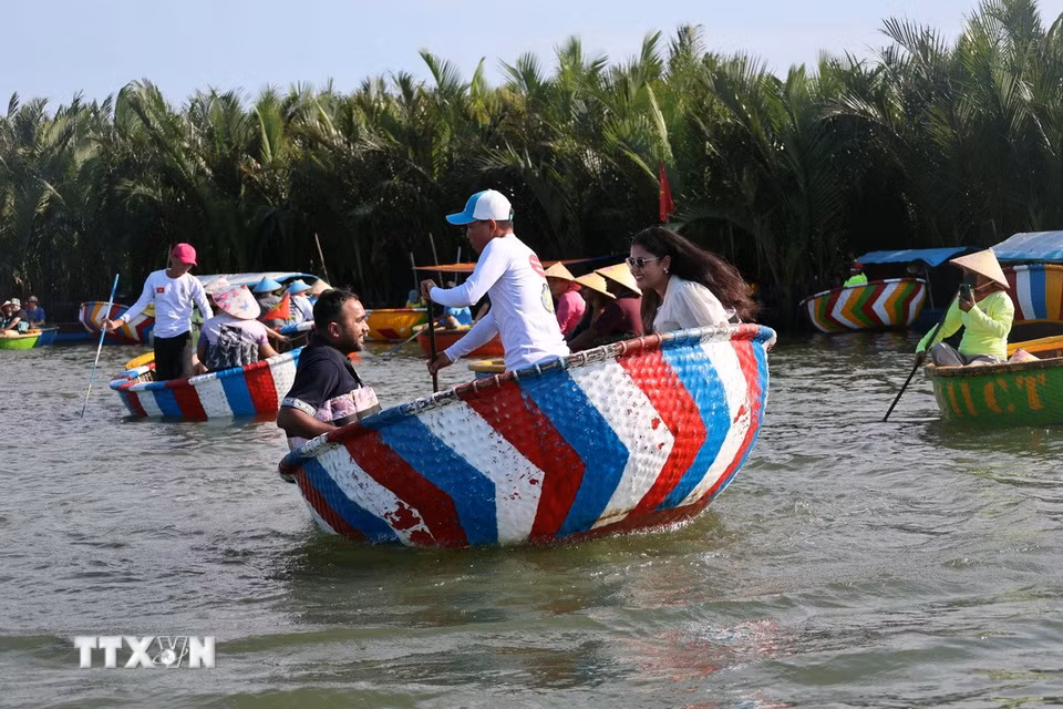 Du khách quốc tế trải nghiệm kỹ năng “lắc thúng” của người dân địa phương ở làng dừa Cẩm Thanh, một trong 50 ngôi làng đẹp nhất thế giới năm 2025. (Ảnh: Đỗ Trưởng/TTXVN)