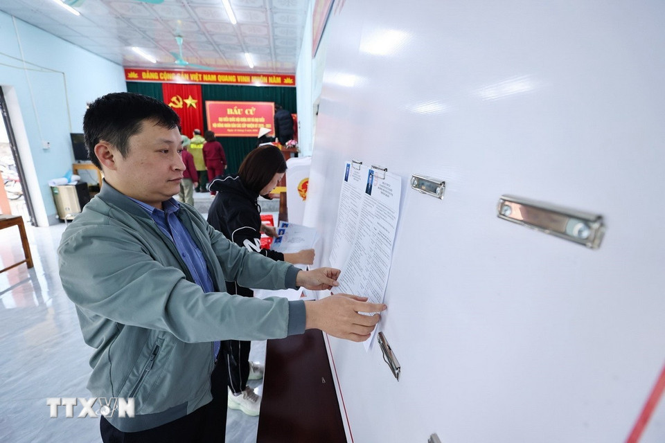 Dán danh sách ứng cử viên, trang trí hội trường, sắp xếp bàn ghế tại nhà văn hóa thôn Nà Khoang 1, xã Quản Bạ. (Ảnh: Minh Đức/TTXVN)