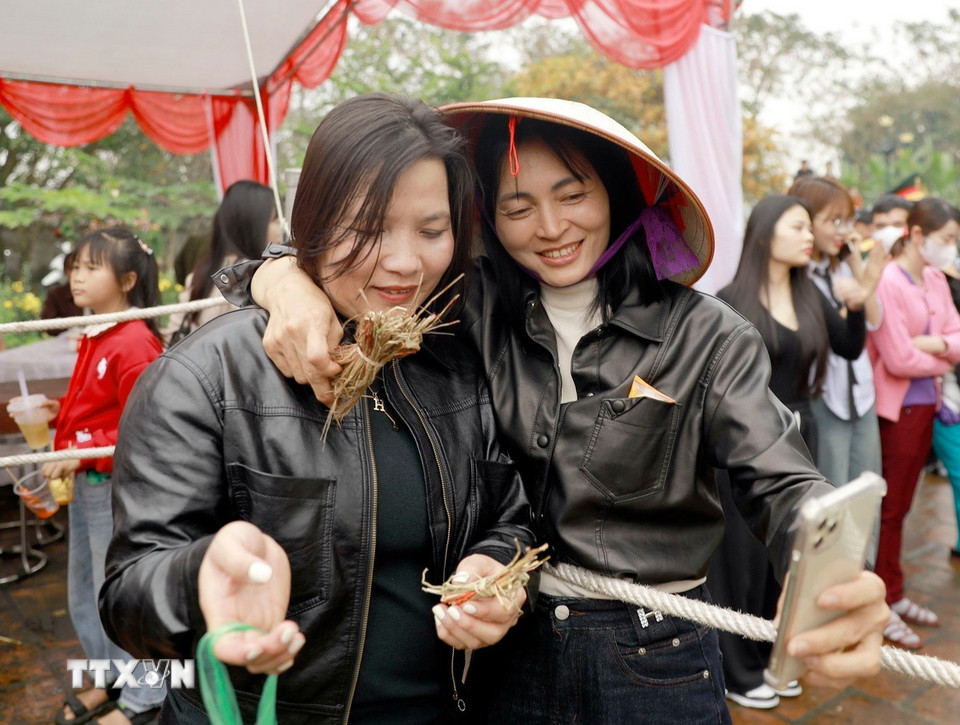 Niềm vui của người dân khi cầm trên tay mảnh chiếu thánh, biểu trưng cho may mắn đầu năm. (Ảnh: Hoàng Hùng/TTXVN)