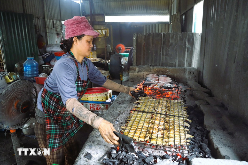 Phụ nữ làng biển Yên Thịnh (xã Diễn Châu, tỉnh Nghệ An) nướng cá biển bằng lửa than hoa tại lò nướng giáp cửa biển Lạch Vạn. (Ảnh: Xuân Tiến/TTXVN)