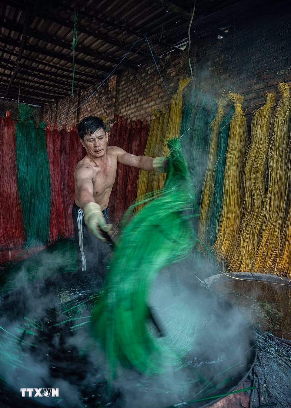 Sợi cói phải được nhúng đều vào nước nhuộm đang đun sôi để giữ được màu tươi lâu hơn. (Ảnh: Khánh Hòa/TTXVN)