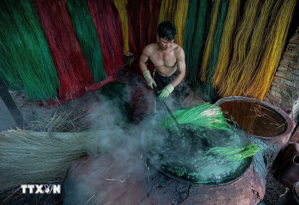 Sử dụng bột màu để nhuộm, sợi cói được nhúng đều vào nước nhuộm đang đun sôi để giữ được màu tươi lâu hơn. (Ảnh: Khánh Hòa/TTXVN)