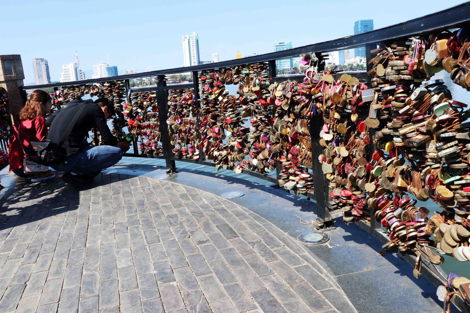 ... với khoảnh khắc cùng nhau “bấm ổ khóa” tình yêu vào lan can trên cầu. (Ảnh: Song Thư/Vietnam+)