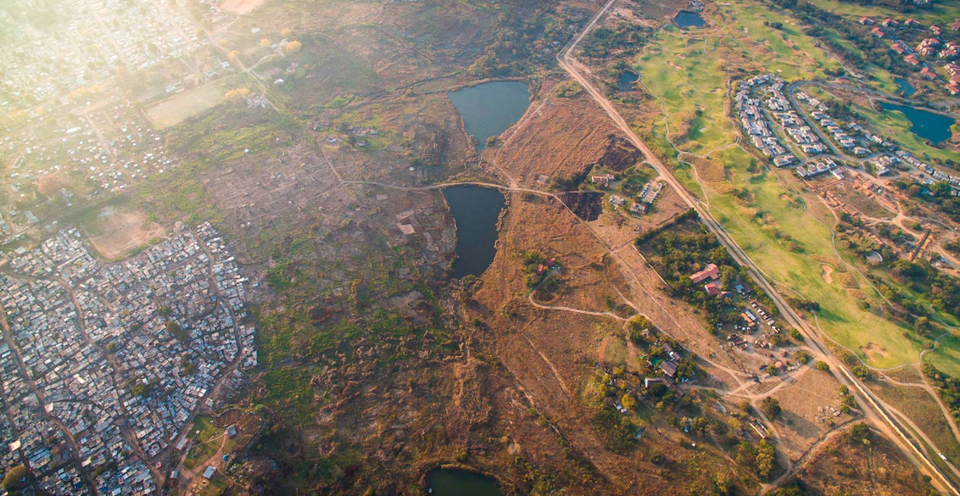 Nhiều cư dân da đen vẫn đang sinh sống trong các khu nhà tạm bằng tôn, xung quanh là đất cát khô cằn cách xa thành phố. (Ảnh: Johnny Miller/​Businessinsider)