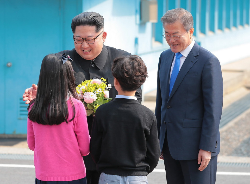 Tổng thống Hàn Quốc Moon Jae-in và Nhà lãnh đạo Triều Tiên Kim Jong-un nhận hoa chúc mừng từ các em thiếu nhi Hàn Quốc tại lễ đón ở quảng trường làng đình chiến Panmunjom ngày 27/4. (Nguồn: YONHAP/TTXVN)