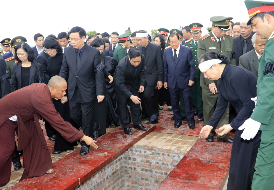 Lãnh đạo, nguyên lãnh đạo Đảng, Nhà nước, Mặt trận Tổ quốc Việt Nam và gia đình Chủ tịch nước Trần Đại Quang thả những nắm đất đầu tiên xuống huyệt mộ Chủ tịch nước. (Ảnh: Nhan Sáng/TTXVN)
