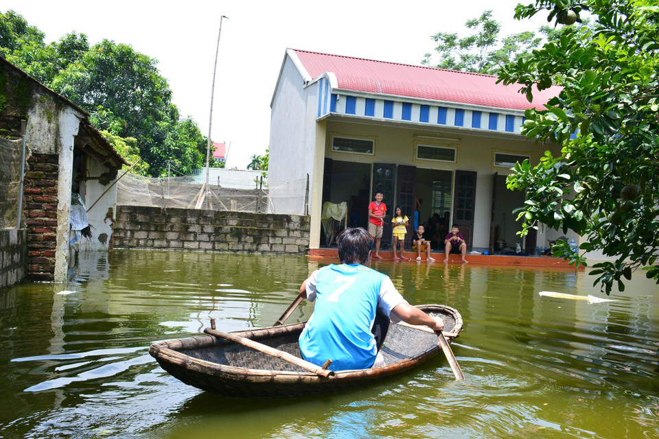 Người dân chèo thuyền ngay ở sân nhà mình. (Ảnh: Quốc Dũng/Vietnam+)