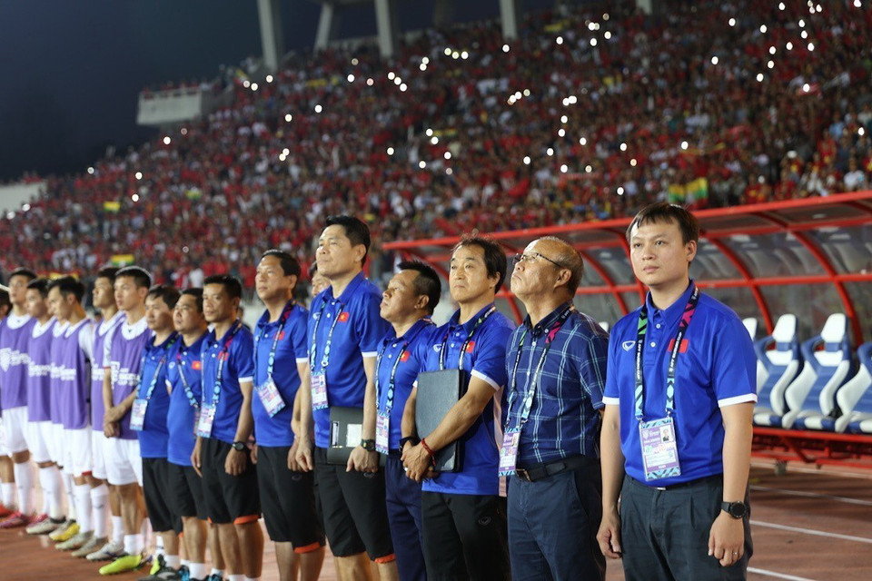 Ban huấn luyện và các cầu thủ dự bị của đội tuyển Việt Nam thực hiện nghi thức chào cờ. (Ảnh: Trọng Đạt/TTXVN)