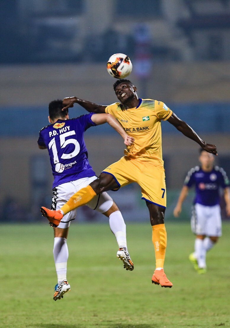 Trong ảnh: Pha tranh chấp bóng bổng của Đức Huy (15, Hà Nội FC) với cầu thủ của đội Sông Lam Nghệ An. (Ảnh: Trọng Đạt/TTXVN)